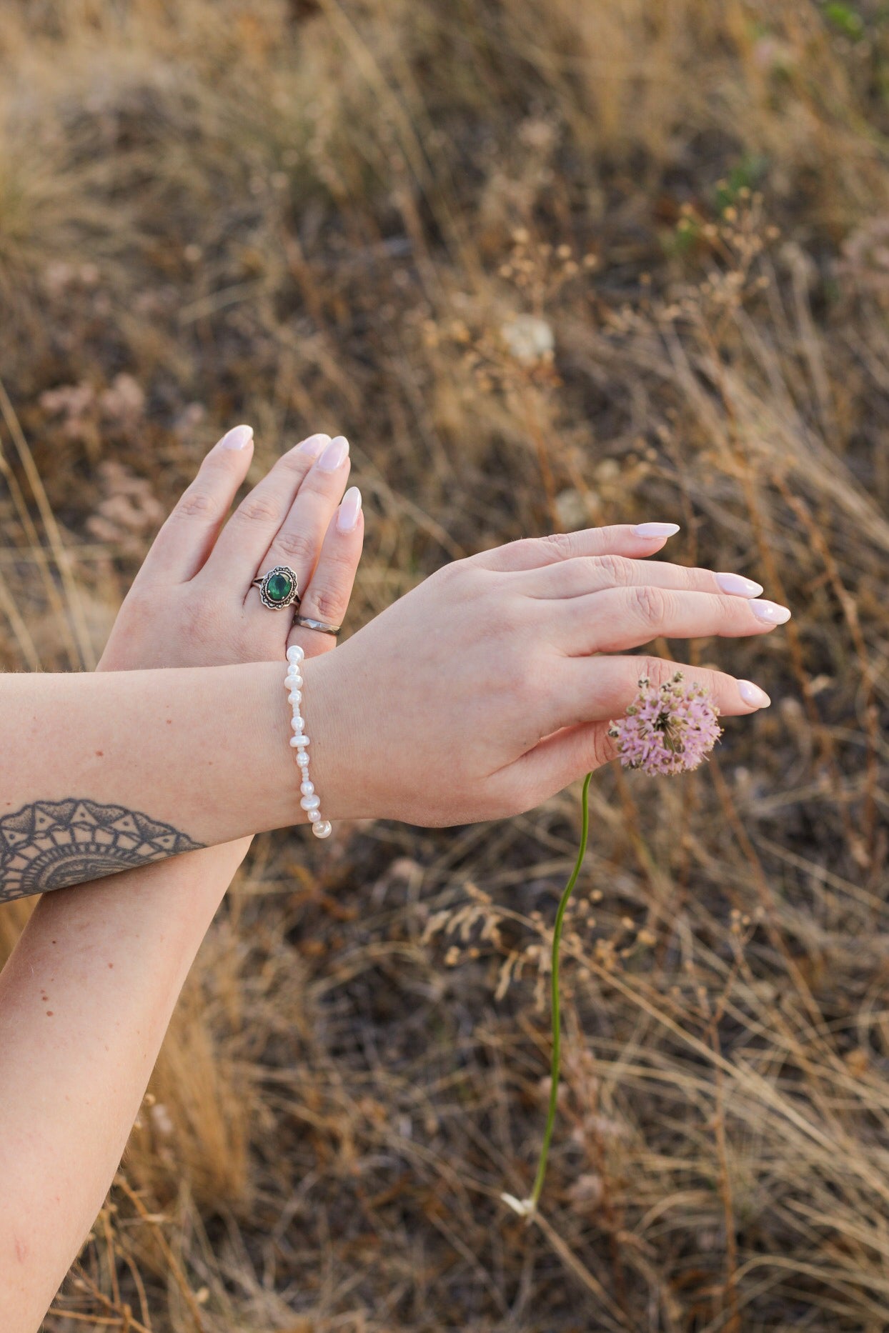 Close-up of hands with rings and a bracelet against a natural background